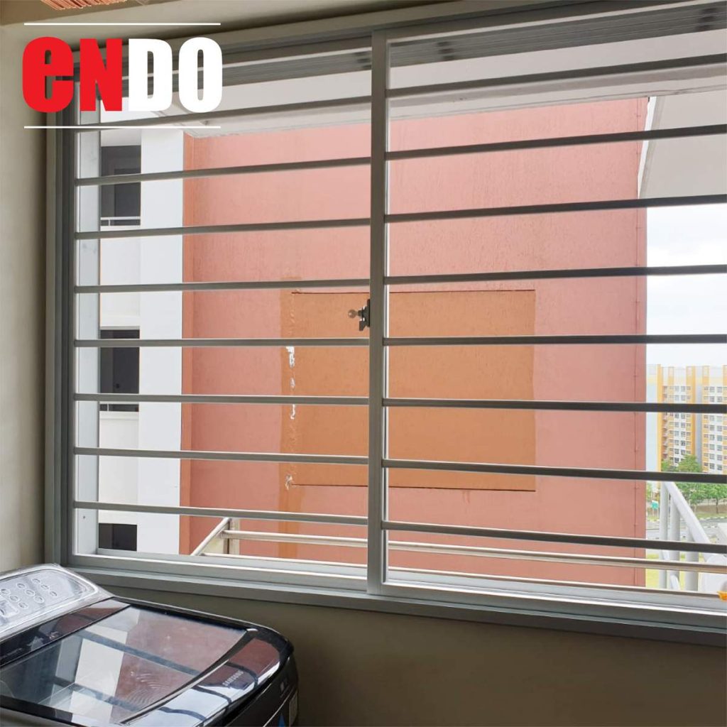 Aluminium window grille at diagonal angle, view of HDB blocks and stadium