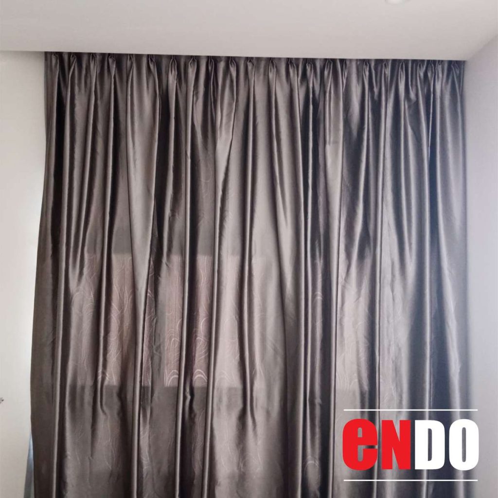 Close-up of grey day and night curtain fabric showing glossy silk texture and pleat detail