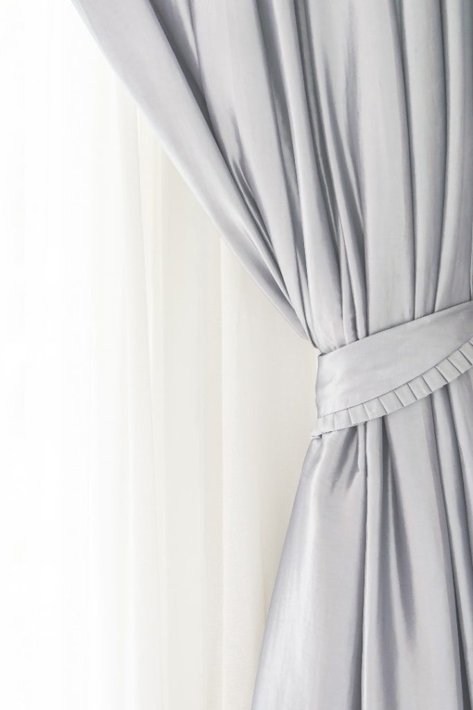 Close-up of a grey curtain tieback with pleated fabric detail