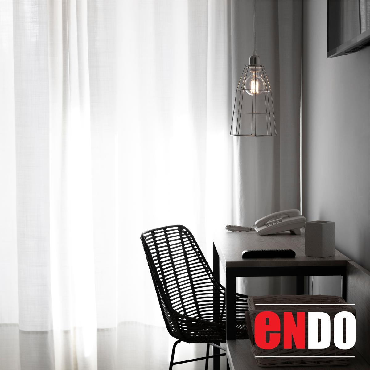 Sheer white day curtains beside a desk and chair in a room