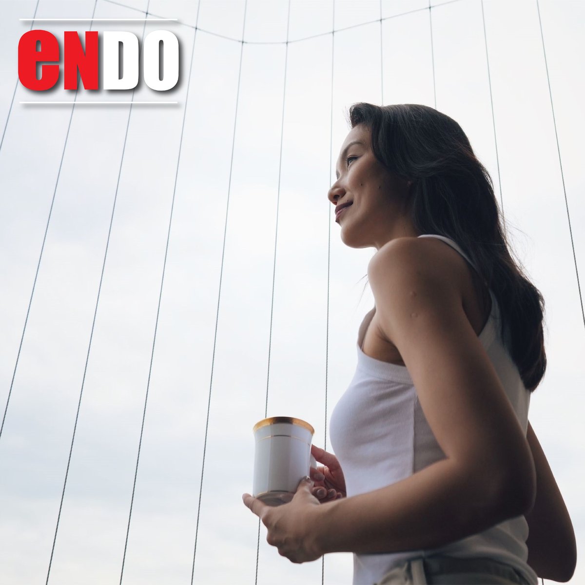 Joanne Peh in profile holding a mug beside invisible grille cables, square crop