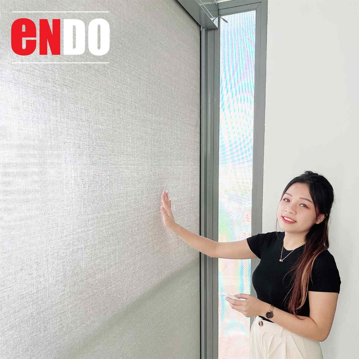 Woman smiling beside a closed motorized zip blind with remote in hand