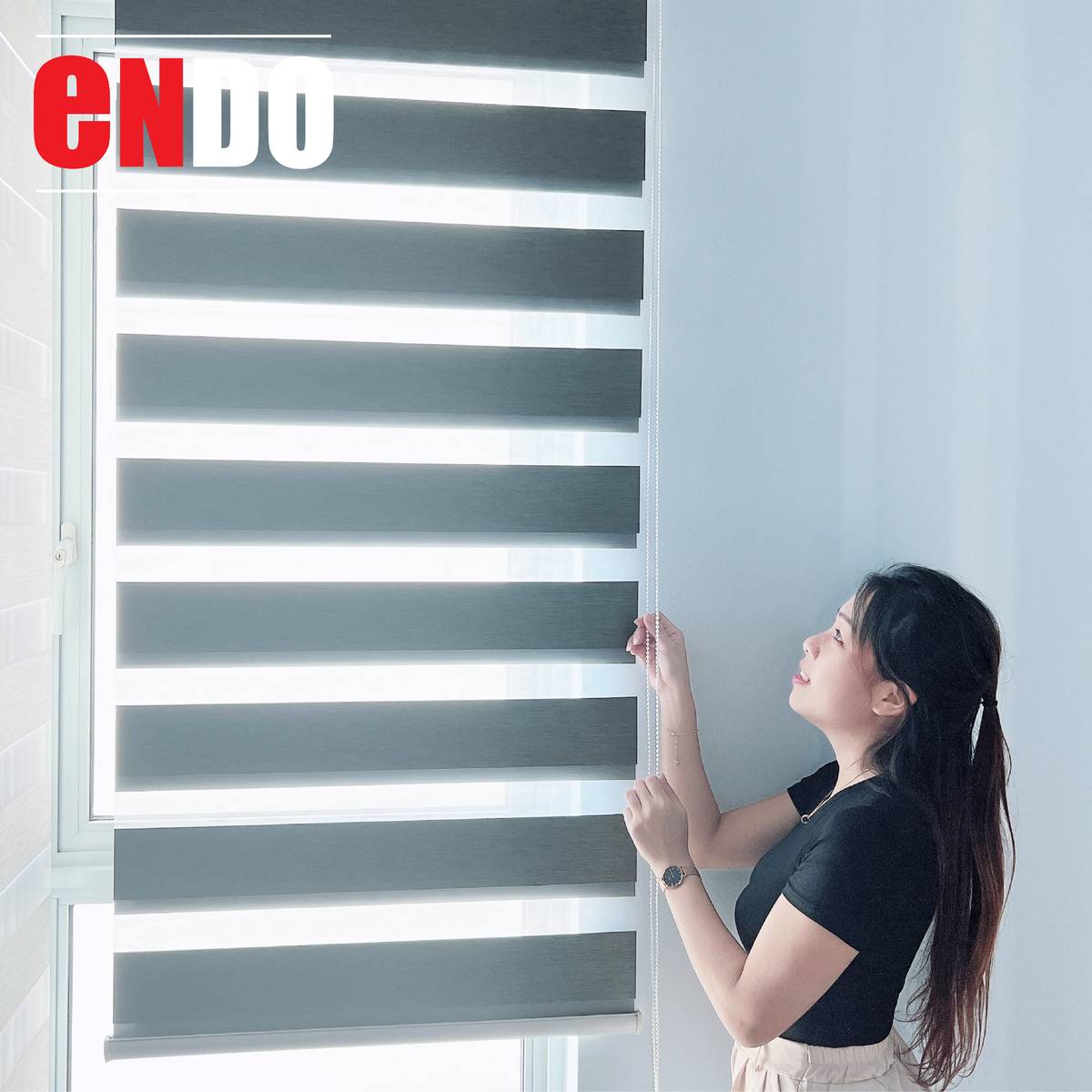 Woman pulling the chain of a dark grey zebra blind